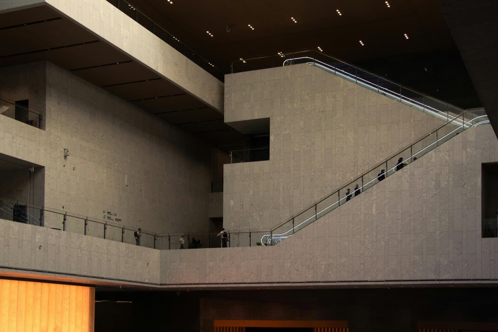 Large civic interior with stone surfaces and quiet escalator lines