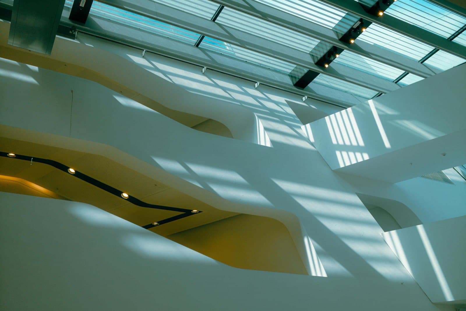 Glass-roofed interior casting architectural shadows across white surfaces